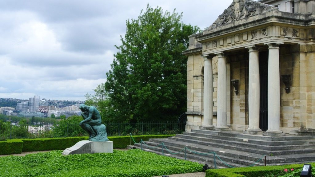Auguste Rodin's Penseur in front of his house in Meudon. The modern towers of la Défense can be seen in the back